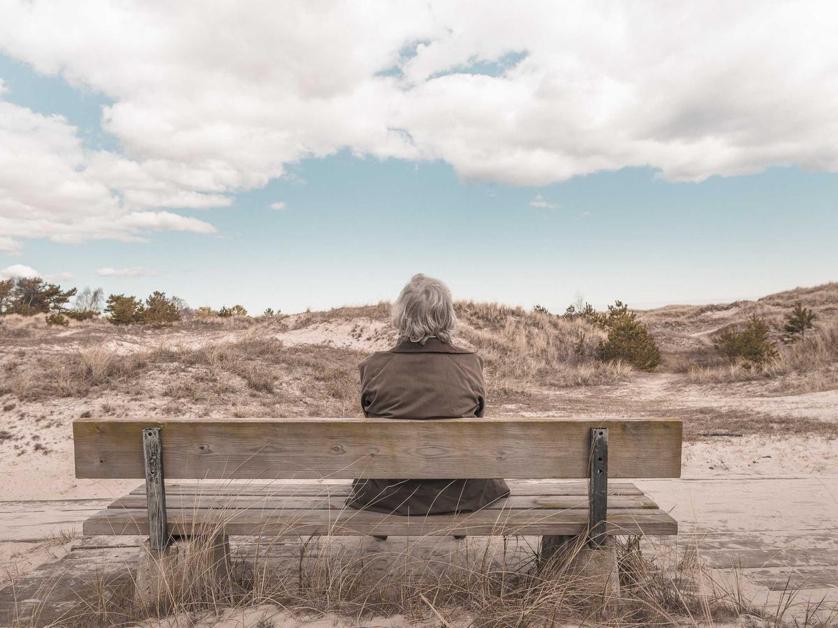 An older woman resting alone on a bench